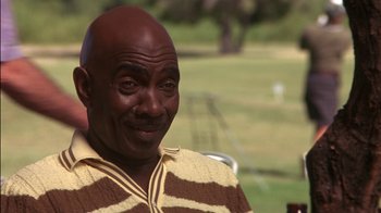Movie still from “Tin Cup” (1996), directed by Ron Shelton – An older man is smiling for the camera; Close Up shot, Low angle