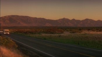 Movie still from “Tin Cup” (1996), directed by Ron Shelton – A road that has some grass on the side of the road; Extreme Wide shot, Low angle