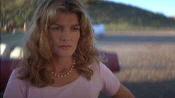 Movie still from “Tin Cup” (1996), directed by Ron Shelton – A woman wearing a pearl necklace looking at the camera; Close Up shot, Low angle