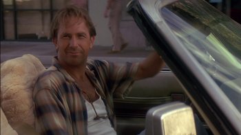 Movie still from “Tin Cup” (1996), directed by Ron Shelton – A man sitting in the driver's seat of a car; Close Up shot, Low angle