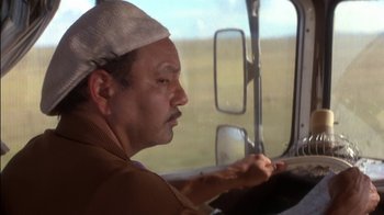 Movie still from “Tin Cup” (1996), directed by Ron Shelton – A man driving a truck on a road; Close Up shot, Low angle