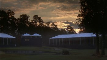 Movie still from “Tin Cup” (1996), directed by Ron Shelton – Two tents in a field at sunset with trees in the background; Extreme Wide shot, Low angle