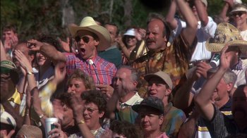 Movie still from “Tin Cup” (1996), directed by Ron Shelton – A group of people sitting in a crowd with hats on; Medium shot, High angle