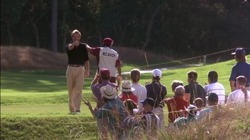 Movie still from “Tin Cup” (1996), directed by Ron Shelton – A group of people sitting and standing on top of a grass covered golf course; Extreme Wide shot, Low angle