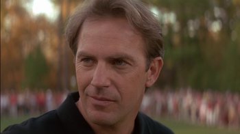 Movie still from “Tin Cup” (1996), directed by Ron Shelton – A person wearing a black shirt; Close Up shot, Over the shoulder angle