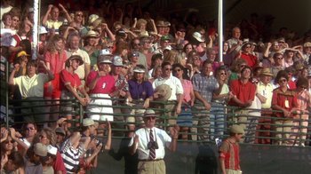 Movie still from “Tin Cup” (1996), directed by Ron Shelton – A group of people standing in a crowd at a sporting event; Wide shot, High angle