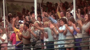 Movie still from “Tin Cup” (1996), directed by Ron Shelton – A group of people standing in a stadium with their hands up; Wide shot, High angle