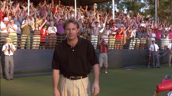 Movie still from “Tin Cup” (1996), directed by Ron Shelton – A man standing in front of a crowd of people; Medium shot, Low angle