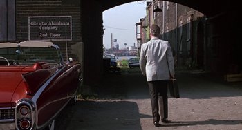 Movie still from “Tin Men” (1987), directed by Barry Levinson – A man walking down a street with a briefcase in his hand; Wide shot, Over the shoulder angle