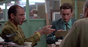 Movie still from “Tin Men” (1987), directed by Barry Levinson – Two men sitting at a table talking to each other; Medium shot, Over the shoulder angle
