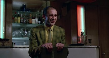 Movie still from “Tin Men” (1987), directed by Barry Levinson – A man wearing a suit and tie smiling; Medium shot, Low angle