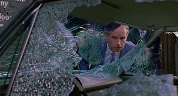 Movie still from “Tin Men” (1987), directed by Barry Levinson – A man in a suit looking through a shattered window; Close Up shot, Low angle