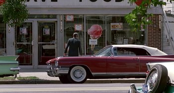 Movie still from “Tin Men” (1987), directed by Barry Levinson – A man walking down the street in front of a car; Wide shot, Low angle