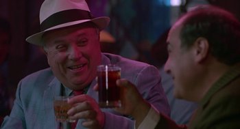 Movie still from “Tin Men” (1987), directed by Barry Levinson – A man wearing a hat and holding a glass of beer; Close Up shot, Over the shoulder angle