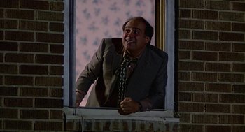 Movie still from “Tin Men” (1987), directed by Barry Levinson – A man in a suit and tie looking out of a window; Medium shot, Low angle