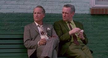 Movie still from “Tin Men” (1987), directed by Barry Levinson – A couple of men sitting next to each other on top of a bench; Medium shot, Low angle