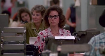Movie still from “Tin Men” (1987), directed by Barry Levinson – A woman sitting in front of an old fashioned typewriter; Medium shot, Low angle