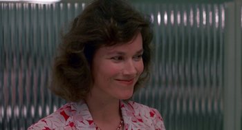 Movie still from “Tin Men” (1987), directed by Barry Levinson – A person wearing a dress smiling; Close Up shot, Over the shoulder angle