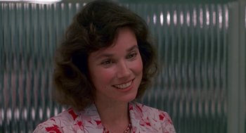 Movie still from “Tin Men” (1987), directed by Barry Levinson – A person wearing a dress smiling; Close Up shot, Over the shoulder angle