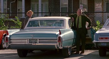 Movie still from “Tin Men” (1987), directed by Barry Levinson – Two men standing in front of an old blue car; Wide shot, Low angle