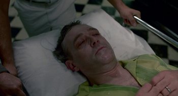 Movie still from “Tin Men” (1987), directed by Barry Levinson – A man laying on a bed with a knife in his hand; Close Up shot, High angle