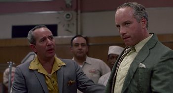 Movie still from “Tin Men” (1987), directed by Barry Levinson – A group of men standing next to each other in a room; Close Up shot, Over the shoulder angle