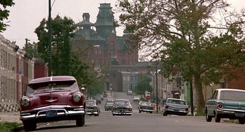Movie still from “Tin Men” (1987), directed by Barry Levinson – Cars are driving down a street in a city; Extreme Wide shot, Low angle