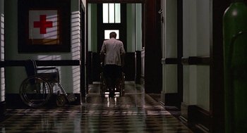 Movie still from “Tin Men” (1987), directed by Barry Levinson – A man in a suit is pushing a wheelchair down a hallway; Wide shot, High angle