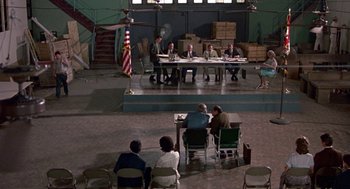 Movie still from “Tin Men” (1987), directed by Barry Levinson – A group of people sitting at a table in front of boxes; Extreme Wide shot, High angle