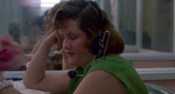 Movie still from “Tin Men” (1987), directed by Barry Levinson – A woman wearing a green shirt is sitting at a table; Close Up shot, High angle