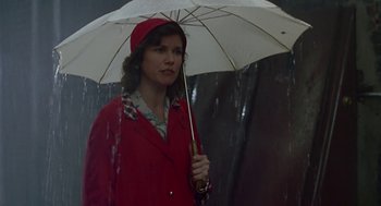 Movie still from “Tin Men” (1987), directed by Barry Levinson – A woman holding an umbrella while standing in the rain; Medium shot, Low angle