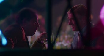 Movie still from “Tin Men” (1987), directed by Barry Levinson – Two people are talking in a room at night; Medium shot, Over the shoulder angle