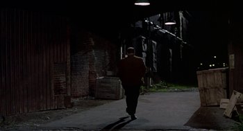 Movie still from “Tin Men” (1987), directed by Barry Levinson – A man walking down a street at night; Wide shot, Over the shoulder angle