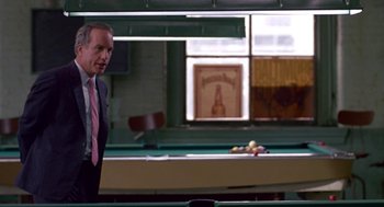 Movie still from “Tin Men” (1987), directed by Barry Levinson – A man in a suit and tie standing in front of a pool table; Medium shot, Over the shoulder angle