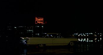 Movie still from “Tin Men” (1987), directed by Barry Levinson – An old car parked on the side of the road at night; Wide shot, Low angle