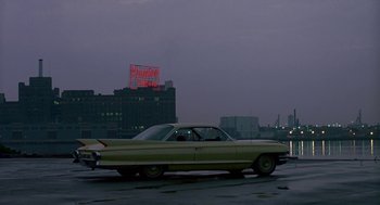 Movie still from “Tin Men” (1987), directed by Barry Levinson – An old car parked on the side of the road at night; Extreme Wide shot, Over the shoulder angle