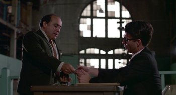 Movie still from “Tin Men” (1987), directed by Barry Levinson – Two men are shaking hands at a table; Medium shot, Low angle