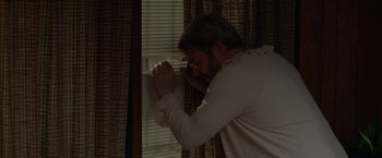 Movie still from “To Dust” (2018), directed by Shawn Snyder – A man leaning against a window sill with his head on the wall; Medium shot, Low angle