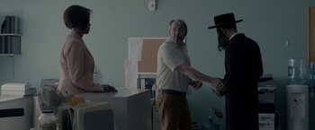 A man shaking hands with another man in a room