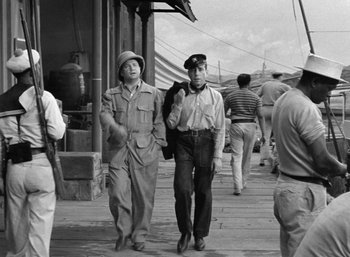 Movie still from “To Have and Have Not” (1944), directed by Howard Hawks – A black and white photo of two men walking down a street; Medium shot, Low angle