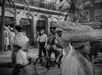 Movie still from “To Have and Have Not” (1944), directed by Howard Hawks – A black and white photo of people on a street; Wide shot, Over the shoulder angle
