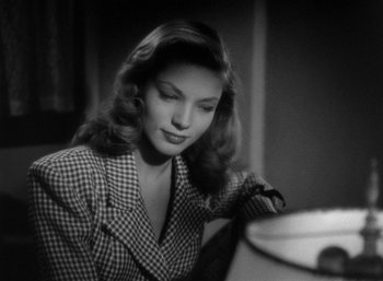 Movie still from “To Have and Have Not” (1944), directed by Howard Hawks – A black - and - white photo of a woman looking down; Close Up shot, Low angle