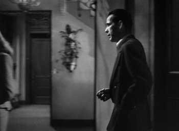 Movie still from “To Have and Have Not” (1944), directed by Howard Hawks – Black and white photograph of a man in a suit; Medium shot, Over the shoulder angle