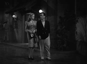 Movie still from “To Have and Have Not” (1944), directed by Howard Hawks – A man and a woman standing next to each other on the sidewalk; Medium shot, Low angle