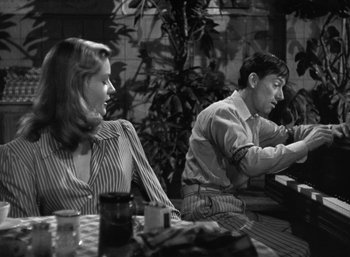 Movie still from “To Have and Have Not” (1944), directed by Howard Hawks – A man and a woman sitting at a table in a restaurant; Medium shot, Low angle