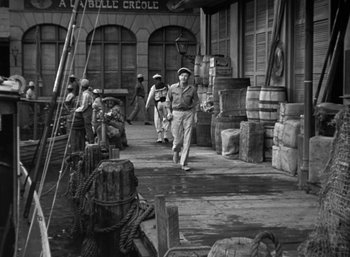 Movie still from “To Have and Have Not” (1944), directed by Howard Hawks – A group of people walking down a street; Wide shot, High angle
