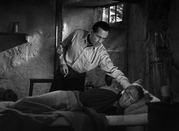 Movie still from “To Have and Have Not” (1944), directed by Howard Hawks – An old photo of a man cutting a man's hair; Medium shot, High angle