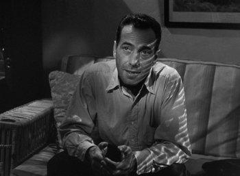 Movie still from “To Have and Have Not” (1944), directed by Howard Hawks – A black and white photo of a man sitting on a couch; Close Up shot, High angle