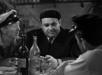 Movie still from “To Have and Have Not” (1944), directed by Howard Hawks – A group of people sitting at a table with bottles of wine; Medium shot, Over the shoulder angle