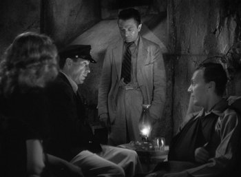 Movie still from “To Have and Have Not” (1944), directed by Howard Hawks – A group of men sitting around a table; Medium shot, High angle